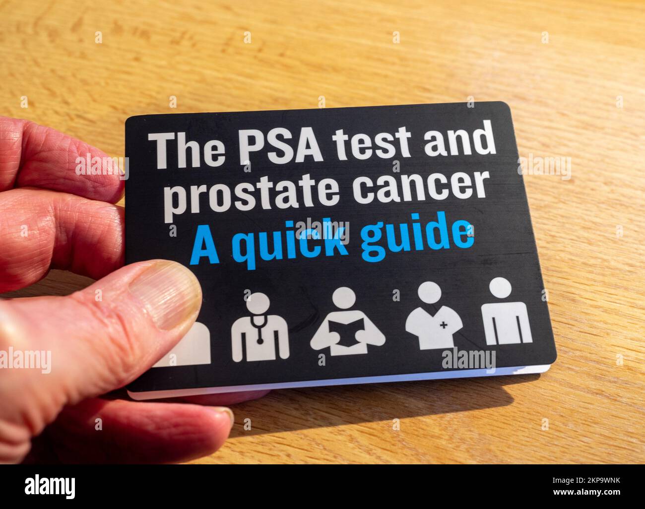 Man's hand holding a PSA test and prostate cancer guide, UK Stock Photo