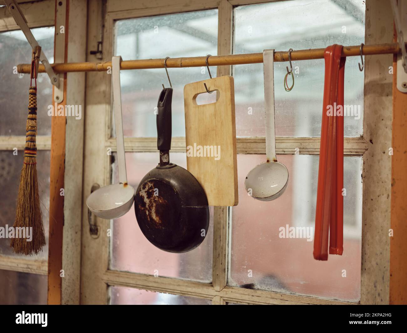 Old kitchen ware hanging on the bar. Different size of pans and kitchen ware on the wall, Home decoration, Kitchen background. Stock Photo