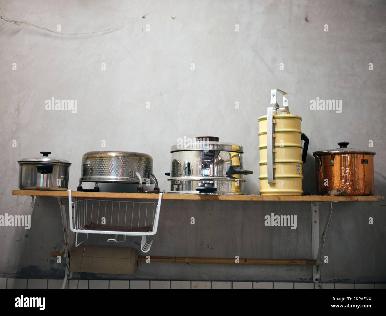 Old kitchen ware hanging on shelf. Different size of pans and kitchen ware on the wall, Home decoration, Kitchen background. Stock Photo