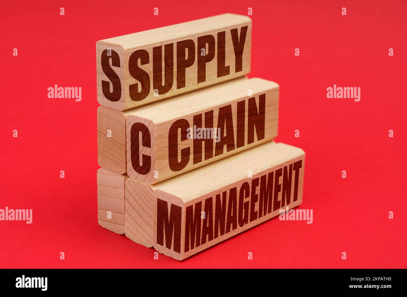 Business and economy concept. On a red background, wooden blocks with the inscription - Supply Chain Management Stock Photo