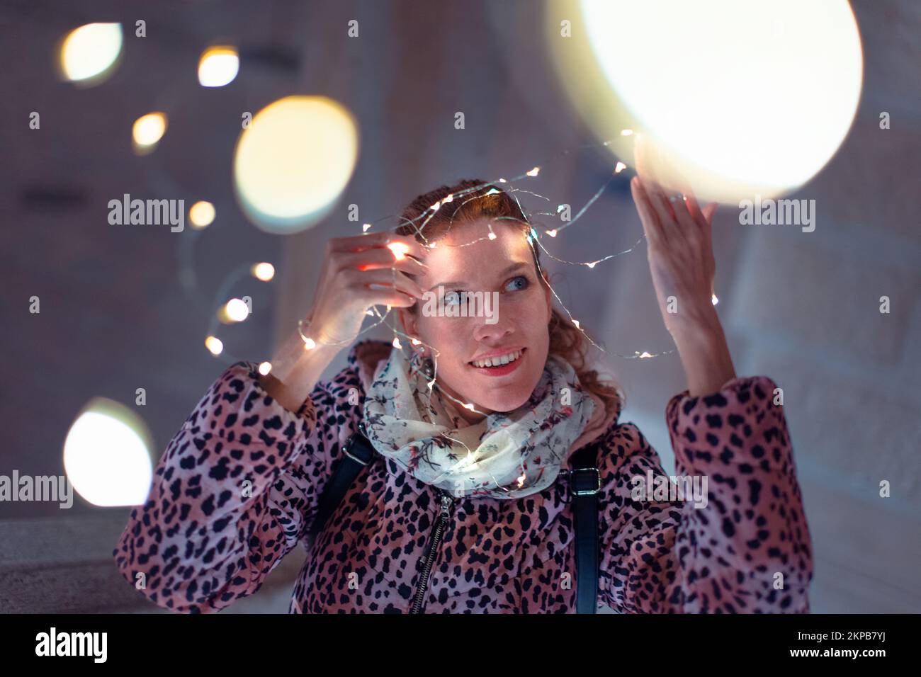 Young 30s Caucasian woman holding LED garland light outdoors Stock Photo