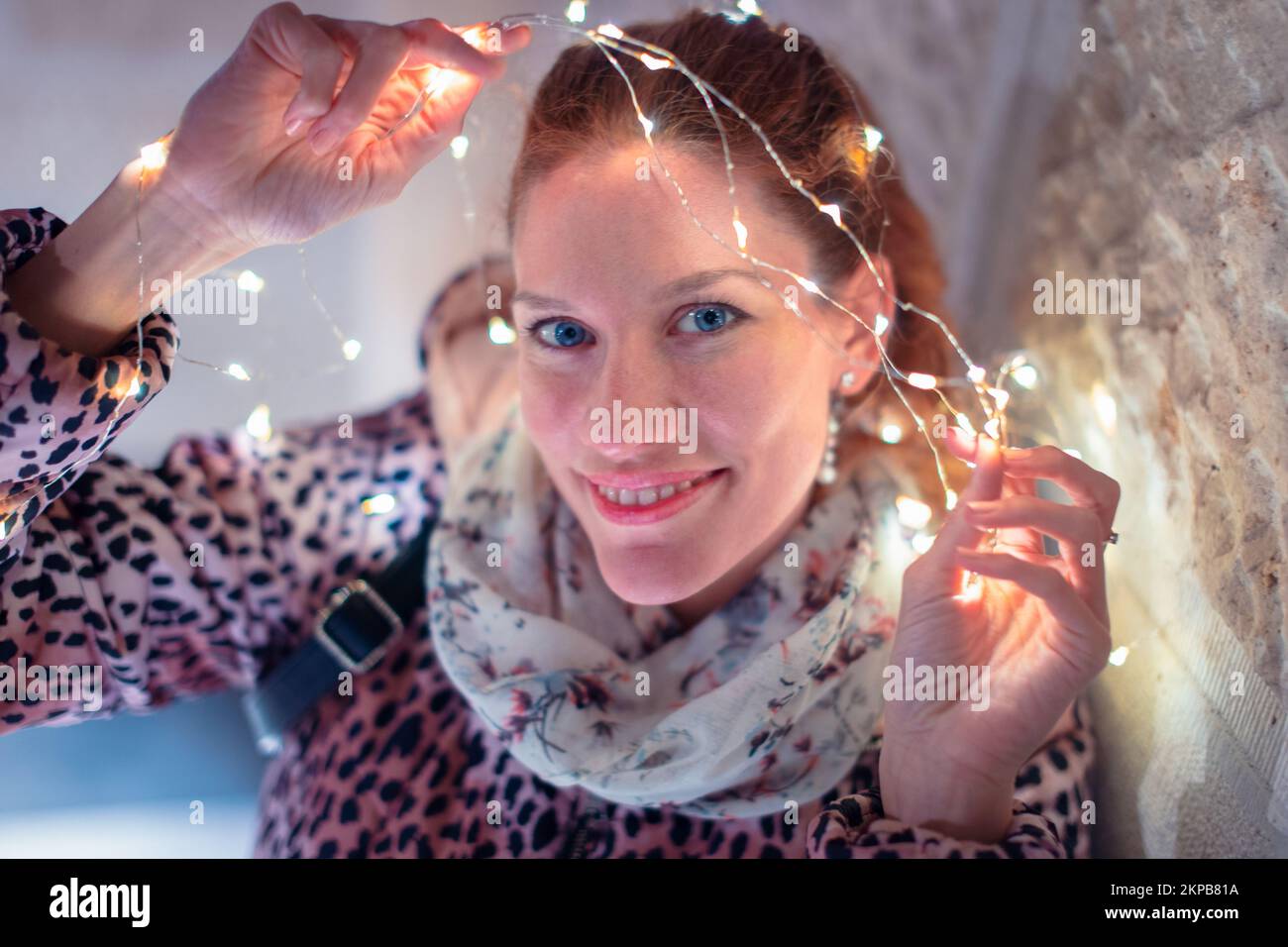 Happy young 30s Caucasian woman holding LED garland light outdoors Stock Photo