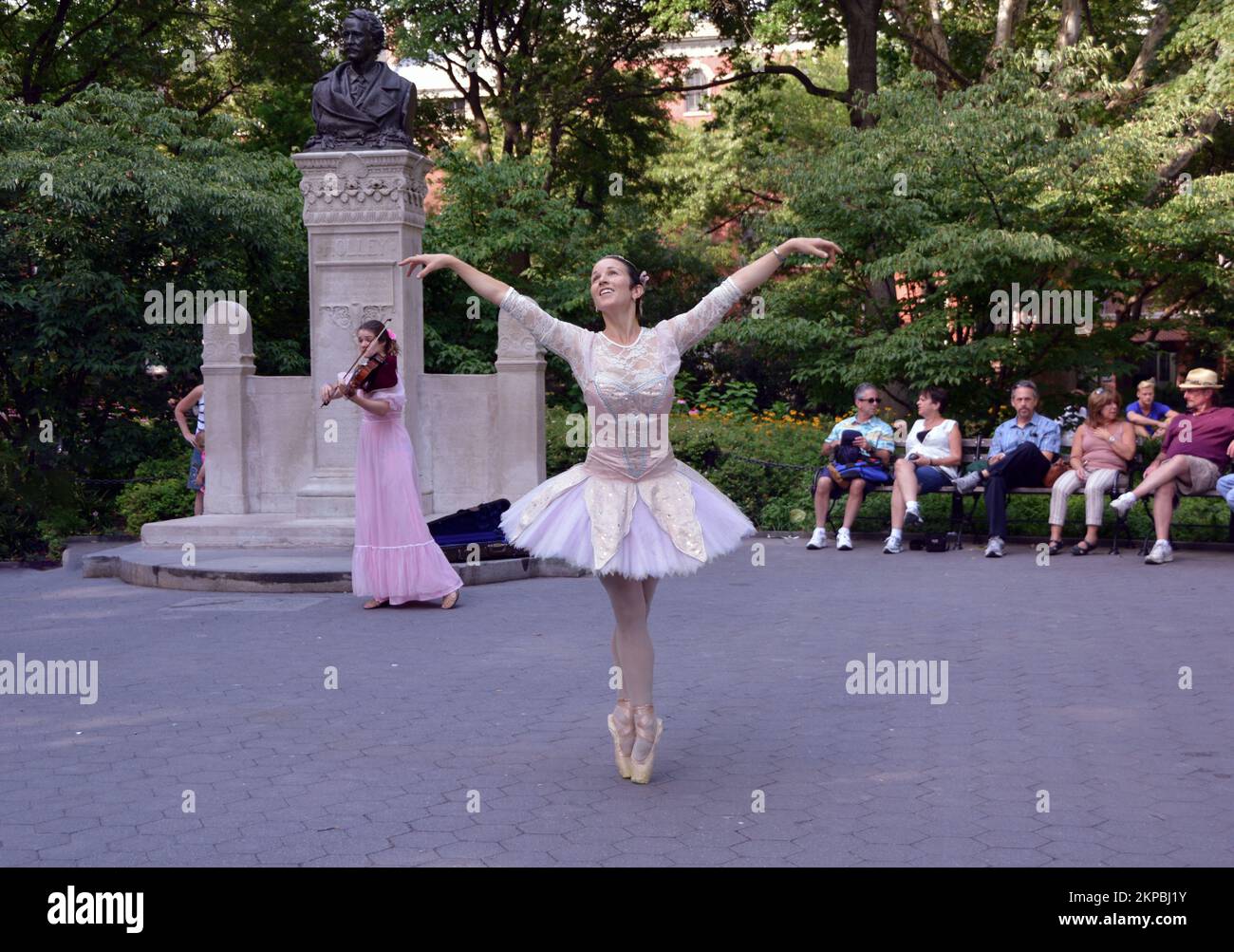 A graceful ballerina backed by a violinist dances in Washington Square