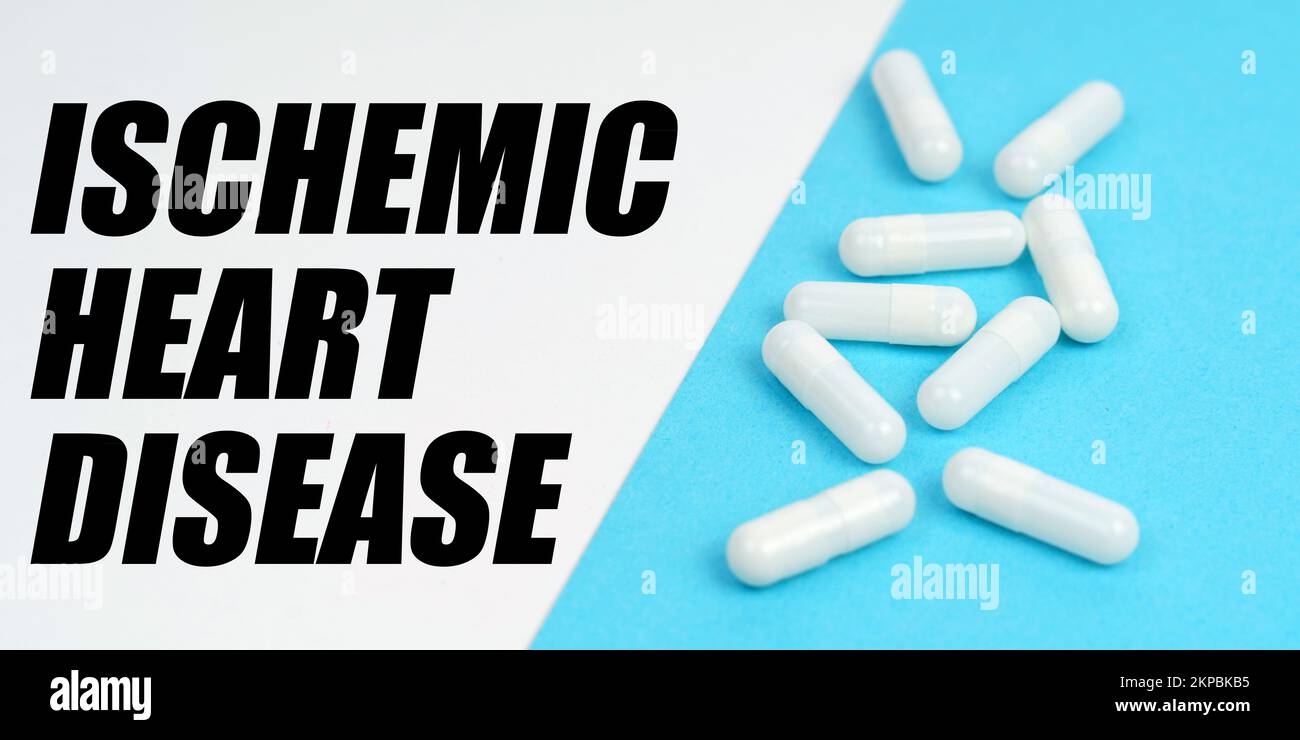Medicine and health concept. There are pills on the blue surface, on the white surface it says - Ischemic Heart Disease Stock Photo