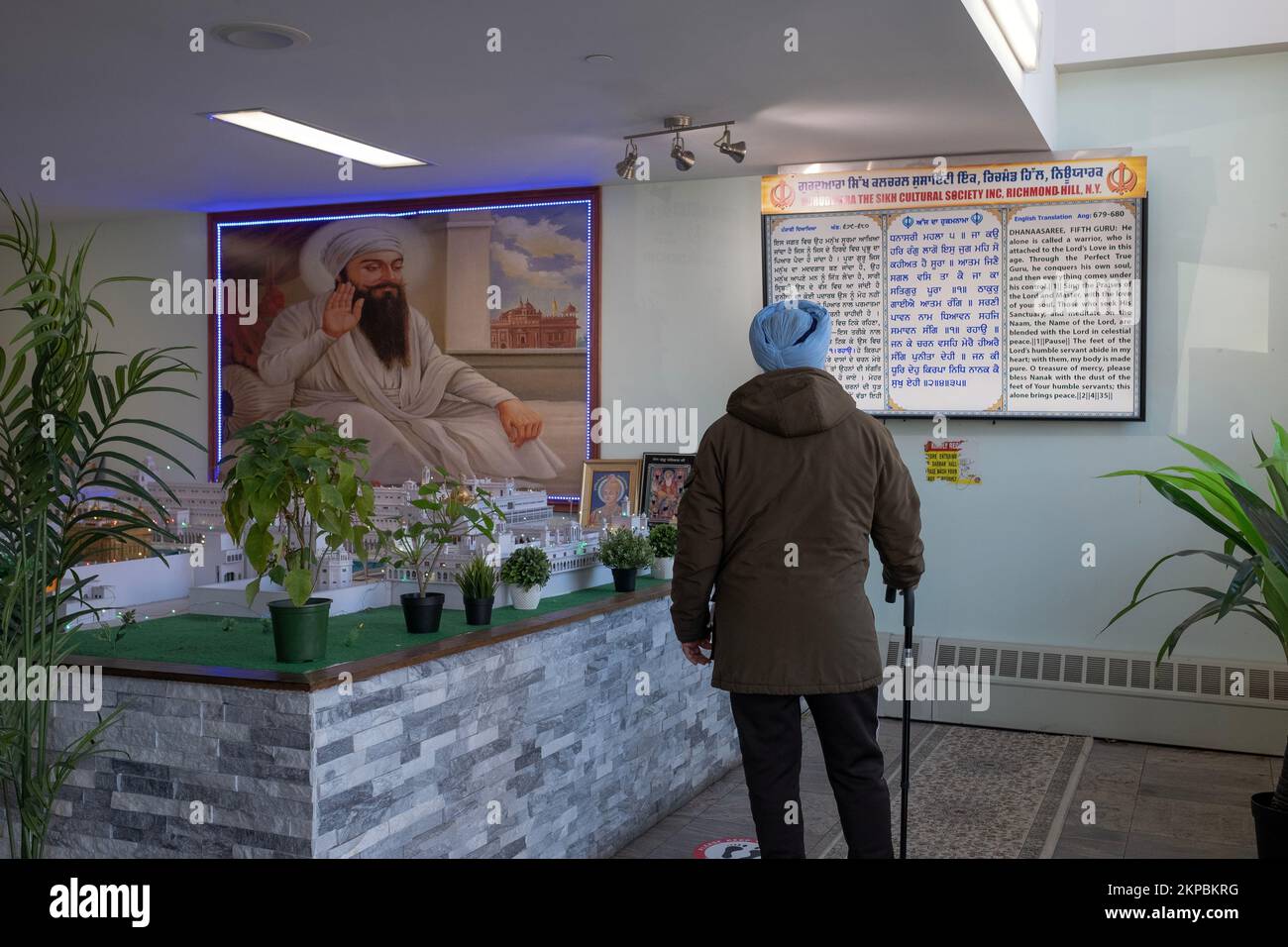 An unidentified older Sikh man reads a trilingual sign at the entrance to the Sikh Cultural Center in Richmond Hill, Queens, New York city. Stock Photo
