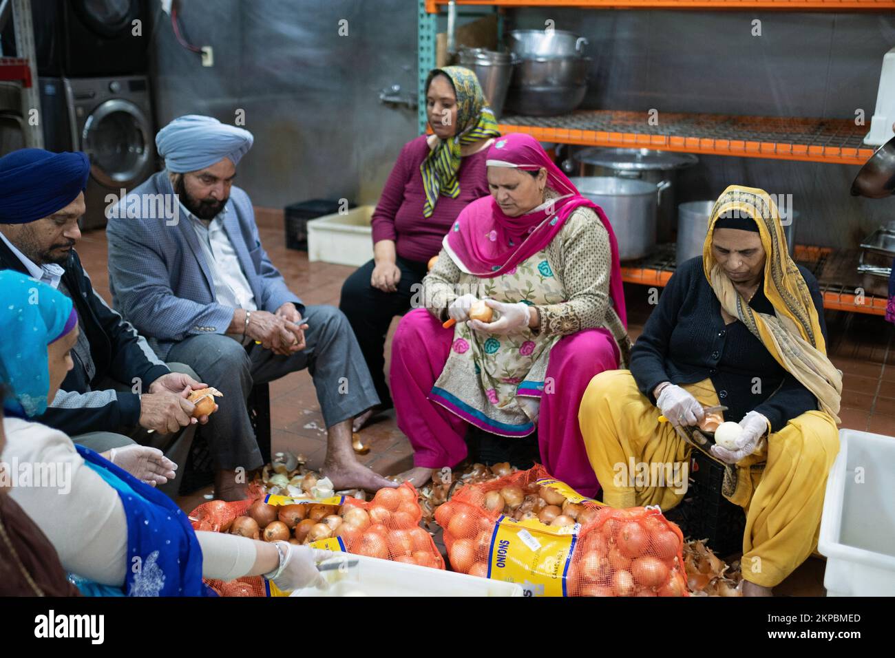 Volunteers peel onions at a Sikh temple langar as part of free meals that will be offered to worshippers, visitors and guests. In Queens, New York. Stock Photo