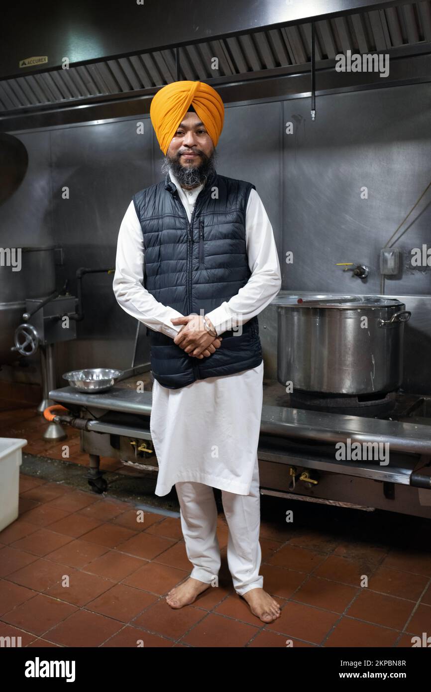 A Sikh priest, a granthi, poses in the langar kitchen at a temple in Richmond Hill, Queens, New York City. Stock Photo