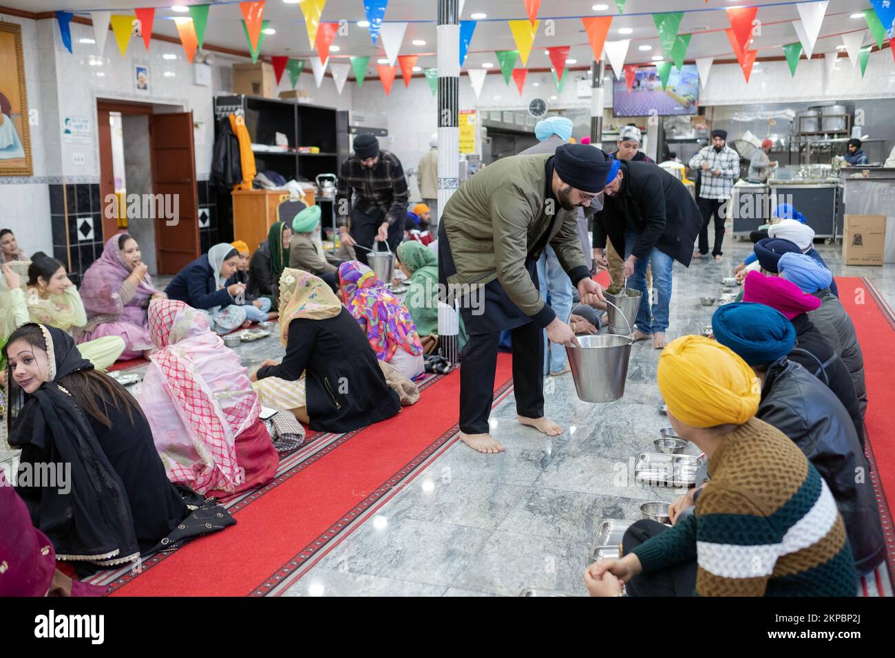 LANGAR. Volunteers at a Sikh temple distribute vegetarian food to worshippers and visitors. At a temple in Richmond Hill, Queens, New York City. Stock Photo