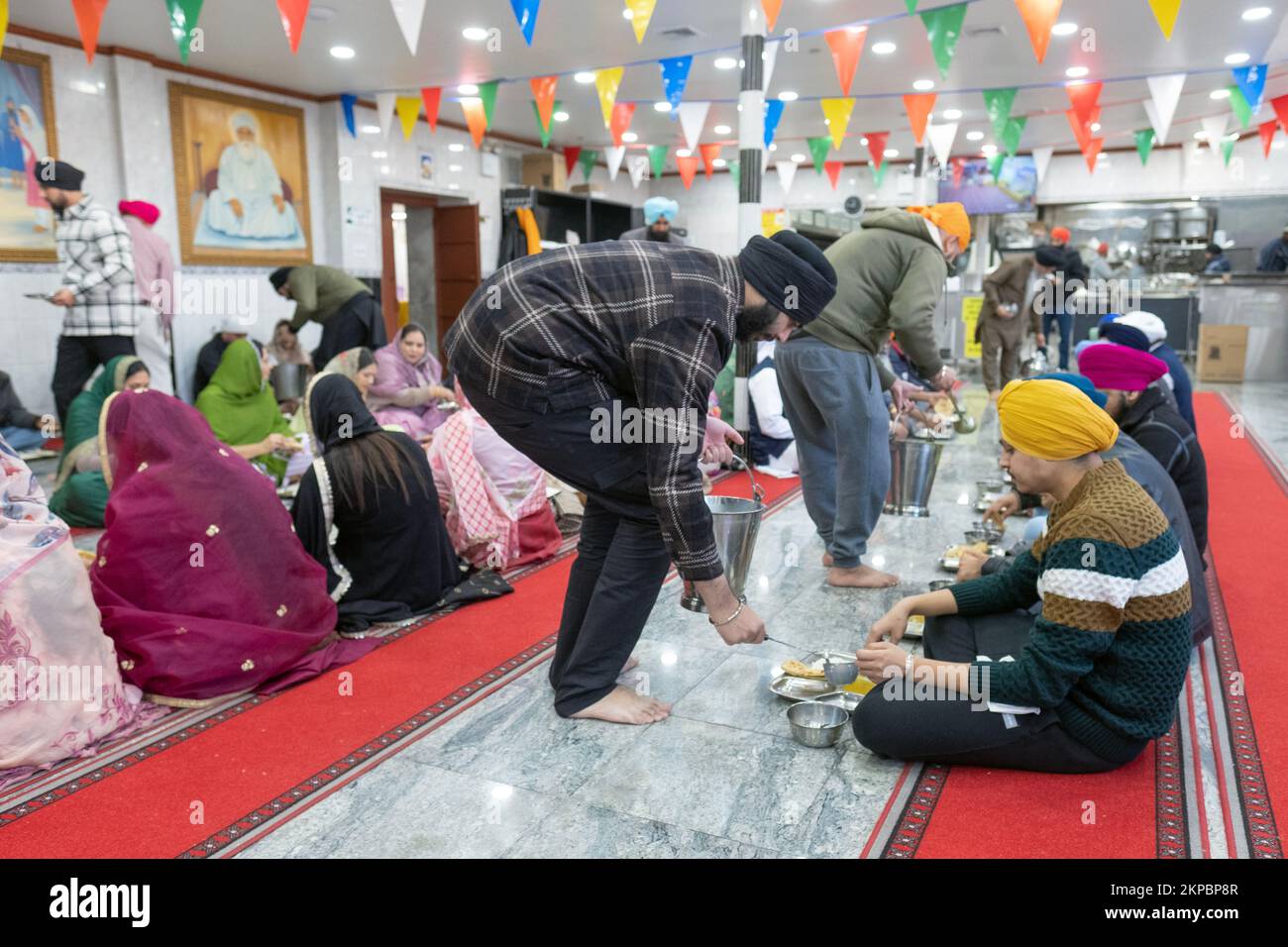 LANGAR. Volunteers at a Sikh temple distribute vegetarian food to worshippers and visitors. At a temple in Richmond Hill, Queens, New York City. Stock Photo