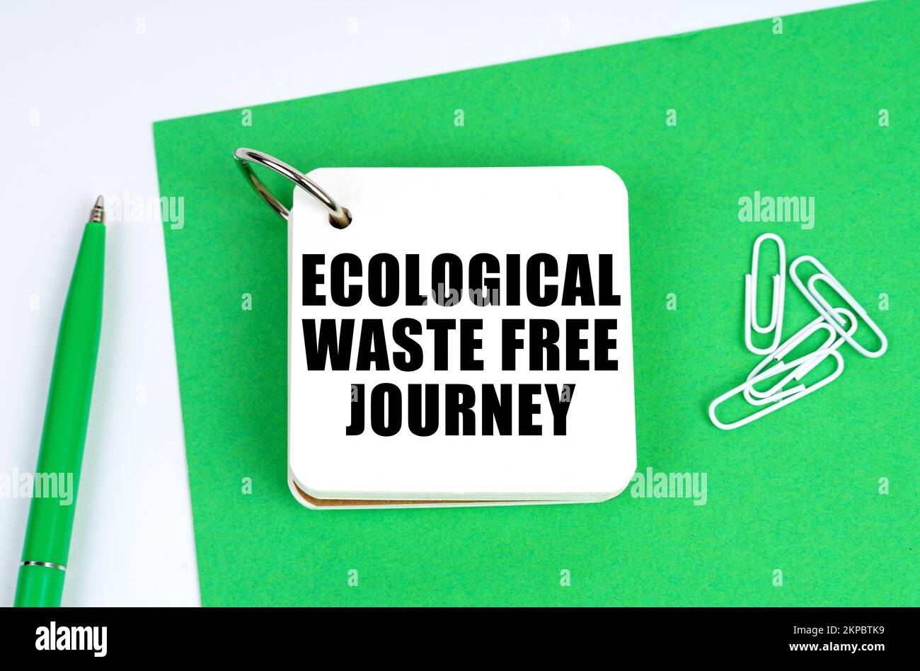 Ecology and industry concept. On a white surface lies a green sheet of paper, a pen and a notebook with the inscription - Ecological Waste Free Journe Stock Photo