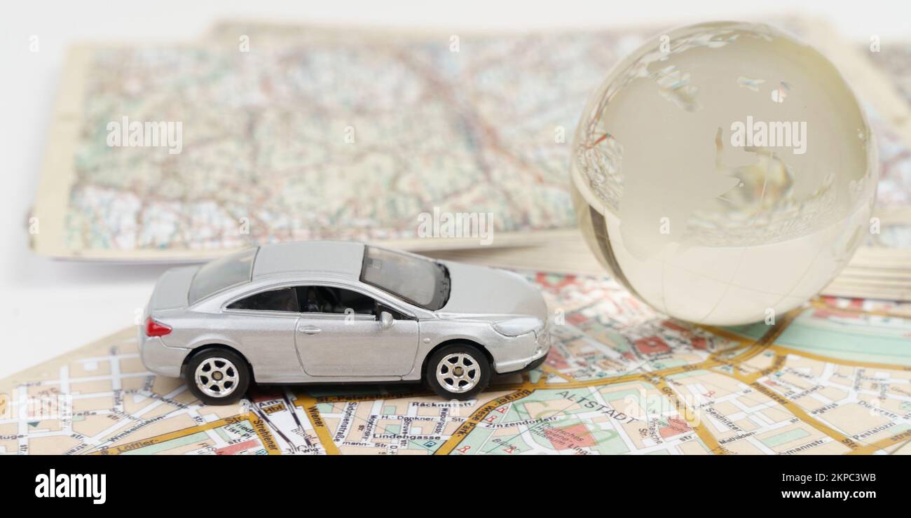 Travel and vacation concept. There is a toy car on the maps next to a glass globe. Travel symbols. Stock Photo