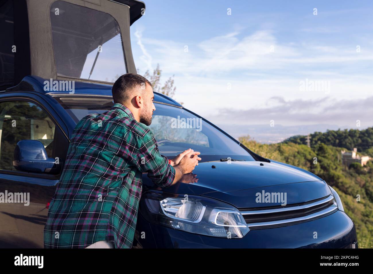 man leaning on his camper van observing nature Stock Photo