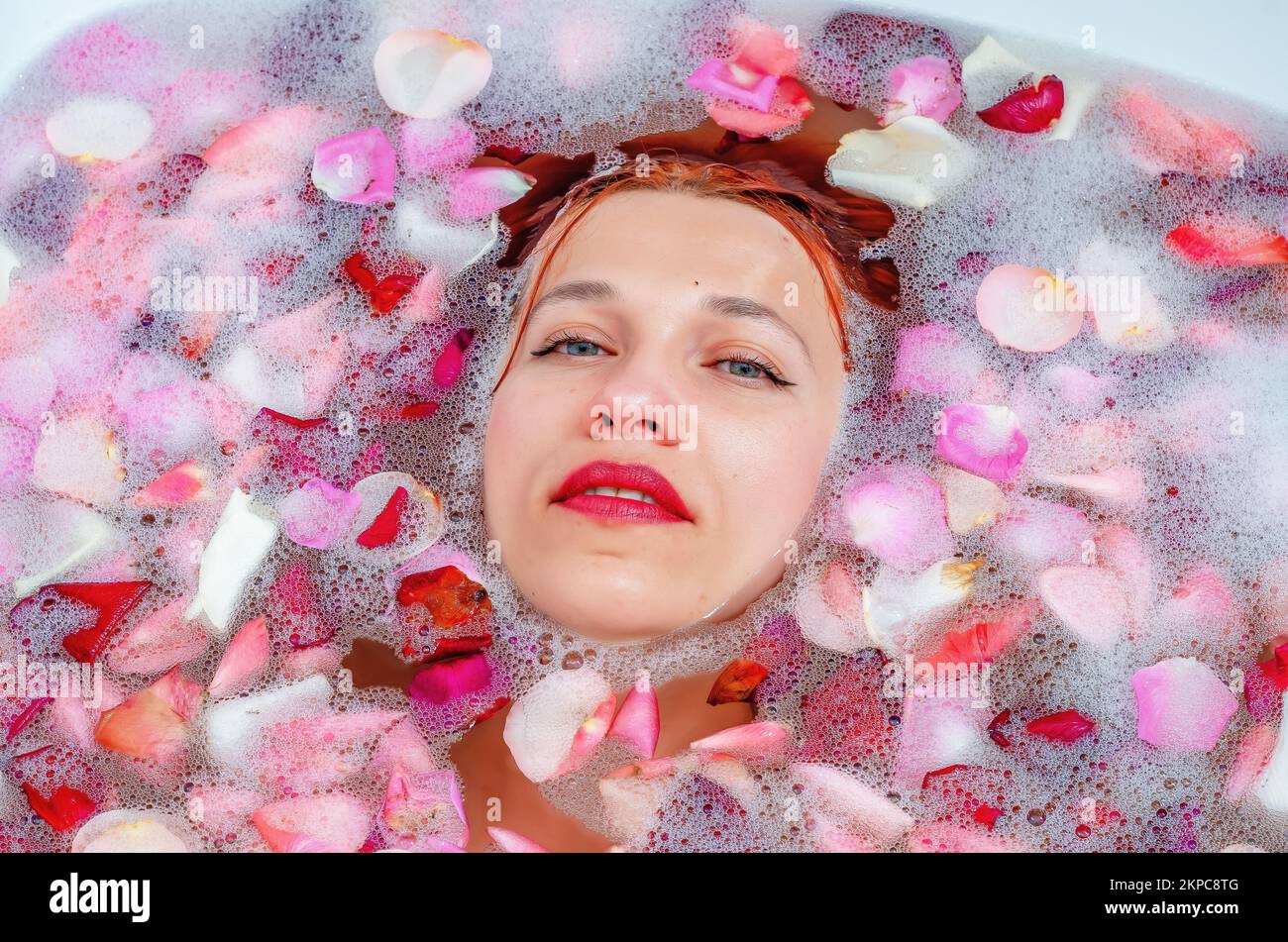 Close up female face in bath with soft white glowing and rose petals. Copyspace for advertising. Beauty, fashion, style, bodycare concept. Attractive Stock Photo