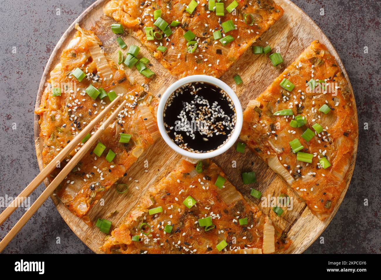 Kimchi-buchimgae or kimchijeon made with sliced kimchi, flour batter and sometimes other vegetables closeup on the wooden board on the table. Horizont Stock Photo