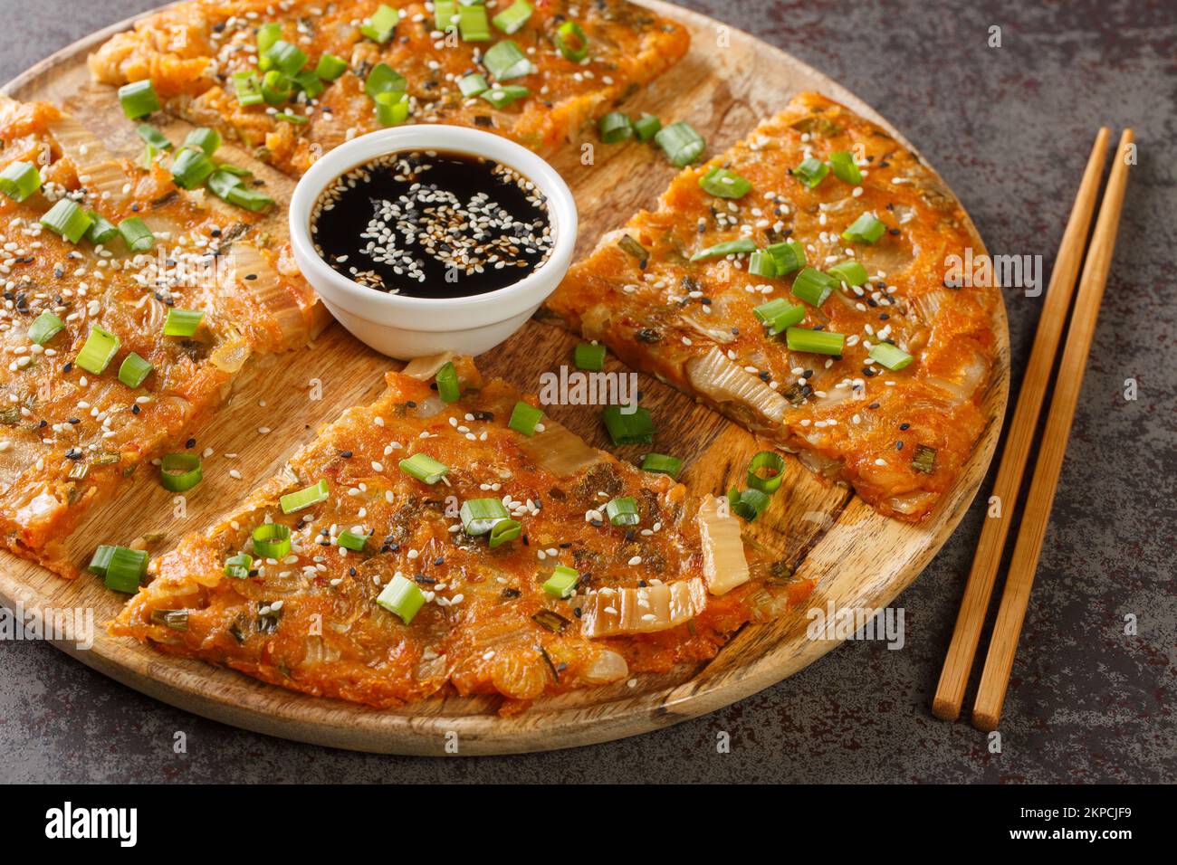 Kimchi-buchimgae or kimchijeon made with sliced kimchi, flour batter and sometimes other vegetables closeup on the wooden board on the table. Horizont Stock Photo