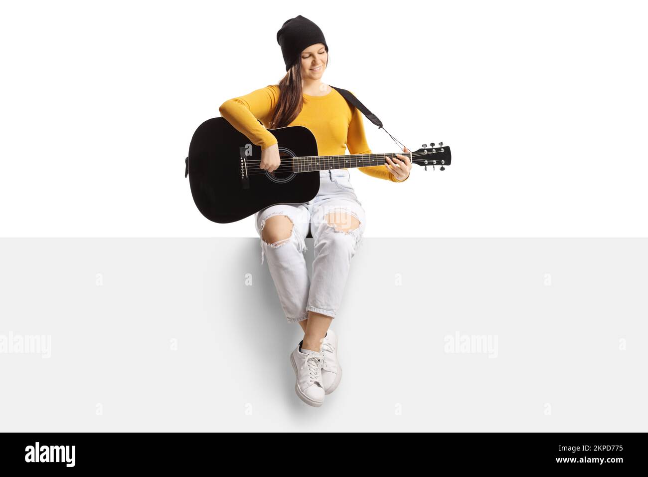Full length portrait of a young trendy female playing an acoustic ...