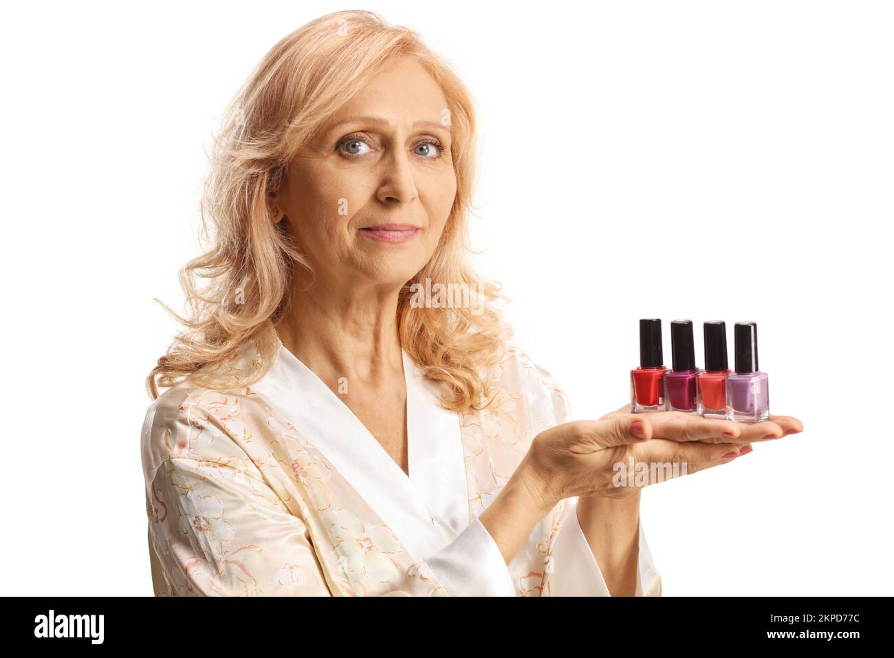 Beautiful mature woman in a bathrobe holding nail polishes isolated on