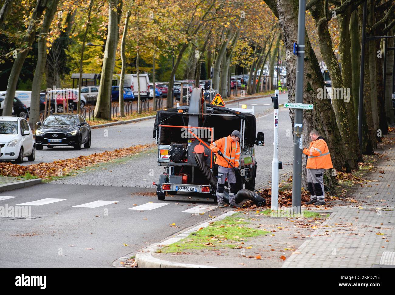Strasbourg, France - Nov 22, 2022: Workers sweeping footpath during autumn using powerful vacuum cleaner to absorb debris and leaves Stock Photo
