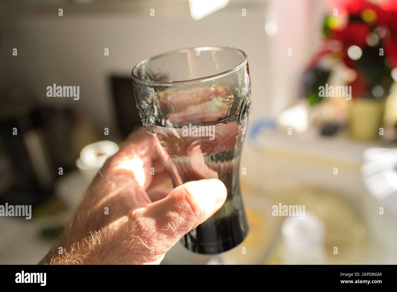 POV personal perspective male hand holding glass of water - gray glass defocused blur bokeh background Stock Photo