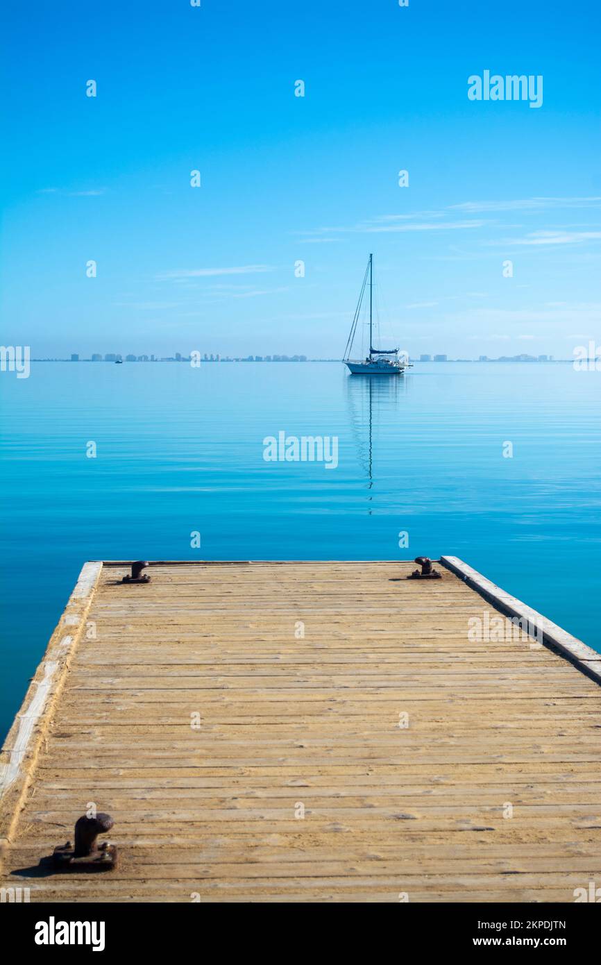 Boat on the still waters of the Mar Menor viewed from a jetty in the Spainsh town of Los alcazares. Stock Photo