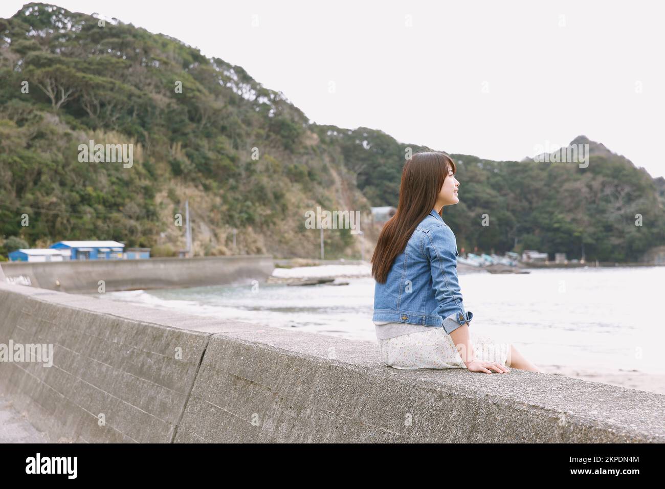 Young Japanese woman sitting on the sea barrier Stock Photo - Alamy