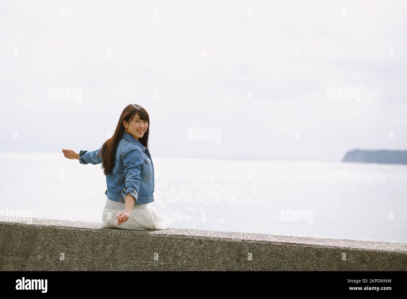 Young Japanese woman sitting on the sea barrier Stock Photo - Alamy