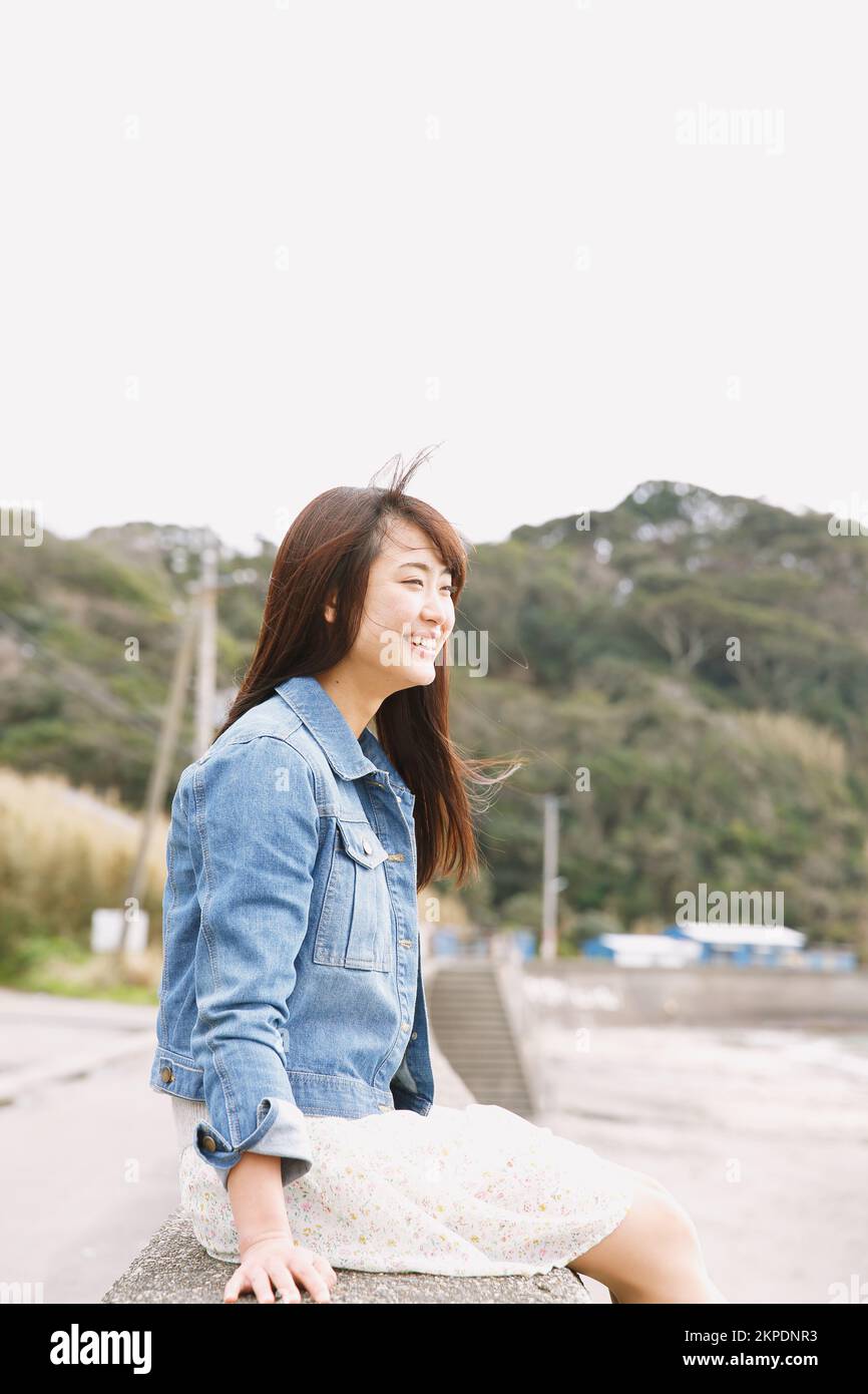 Young Japanese woman sitting on the sea barrier Stock Photo - Alamy