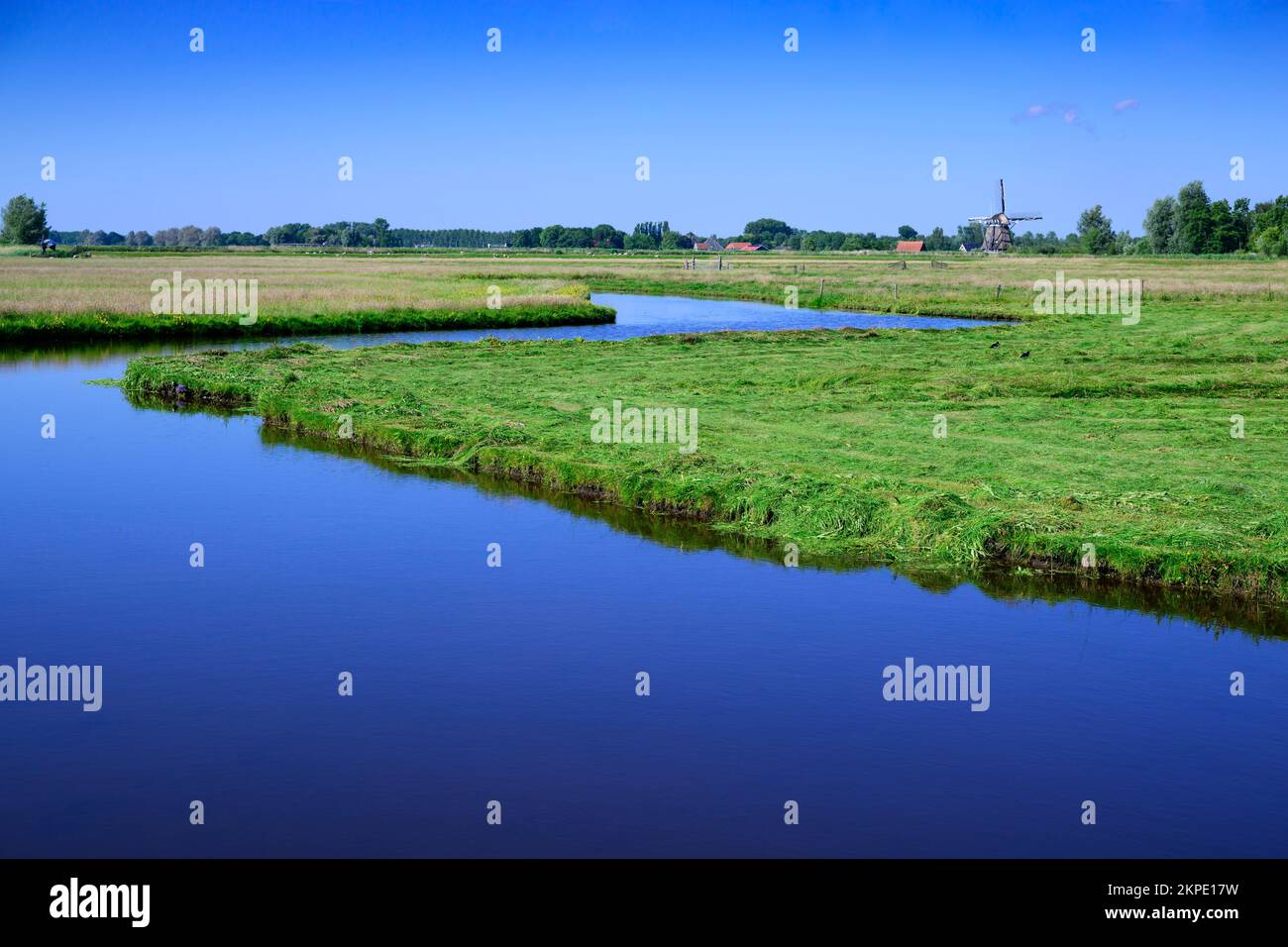 Authentic dutch river landscape with green meadows, water and blue sky, Netherlands. Stock Photo