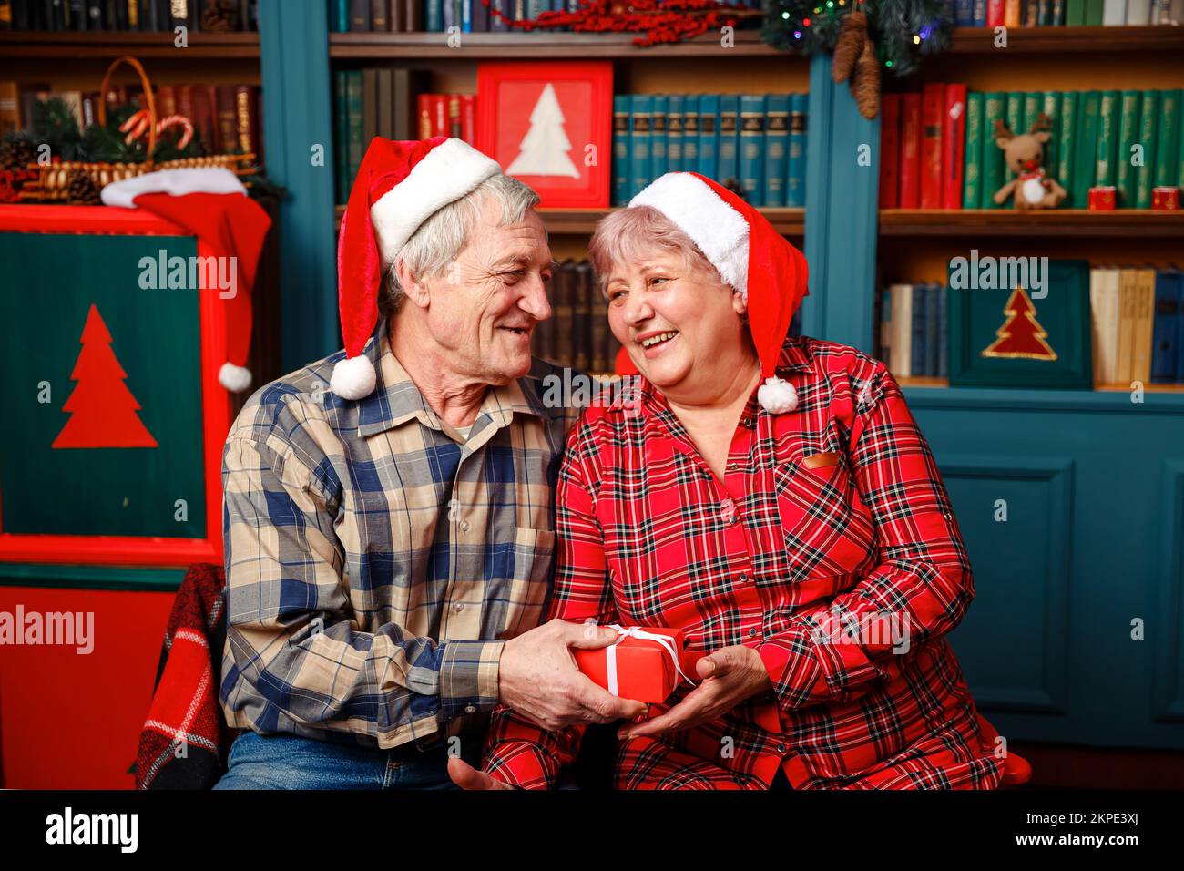 Photo of Happy senior couple exchanging Christmas presents at home. Stock Photo