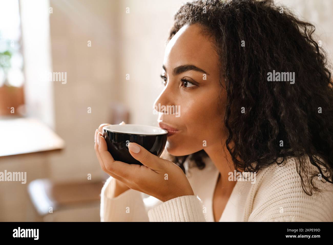 Young black woman drinking coffee while sitting in cafe indoors Stock ...