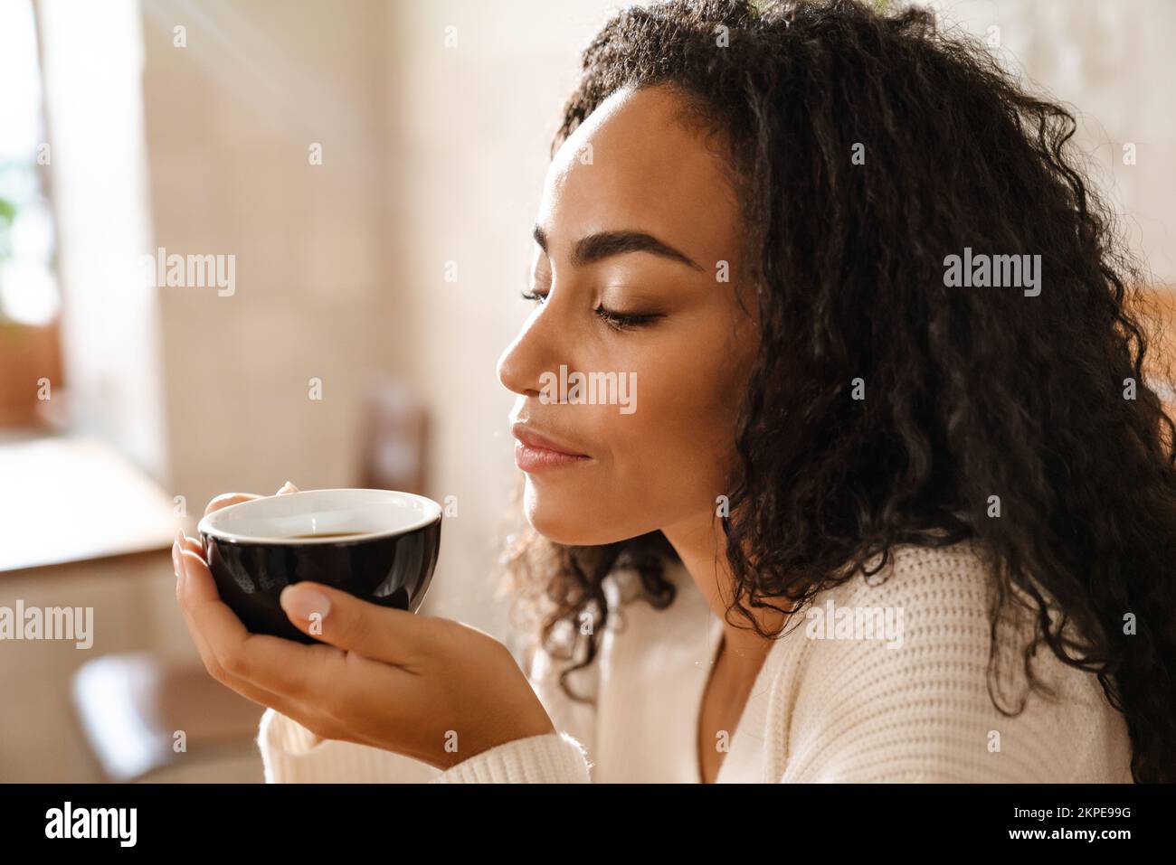 Young black woman drinking coffee while sitting in cafe indoors Stock ...
