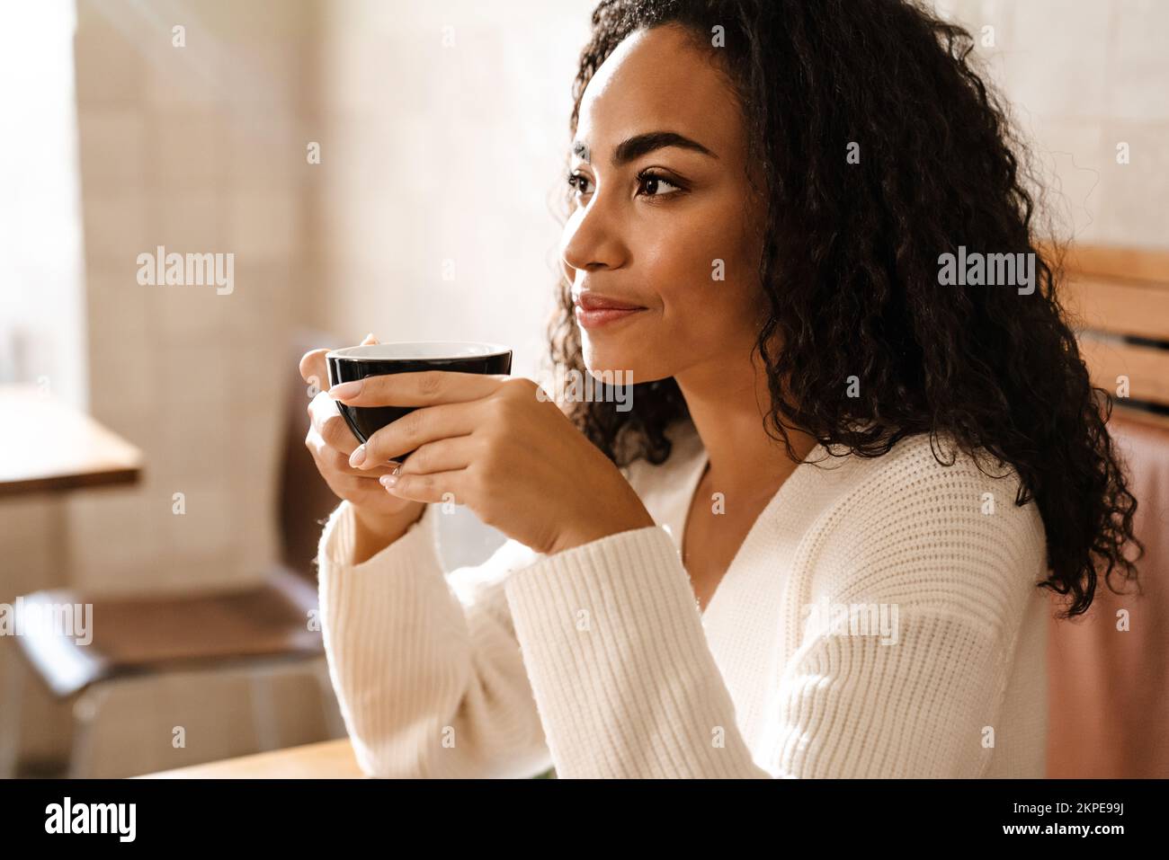 Young black woman drinking coffee while sitting in cafe indoors Stock ...