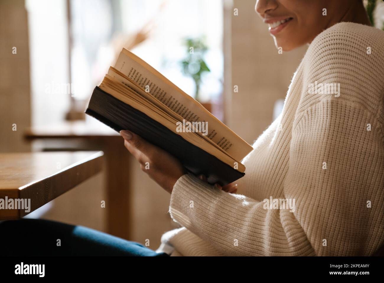 Young black woman smiling and reading book in cafe indoors Stock Photo ...