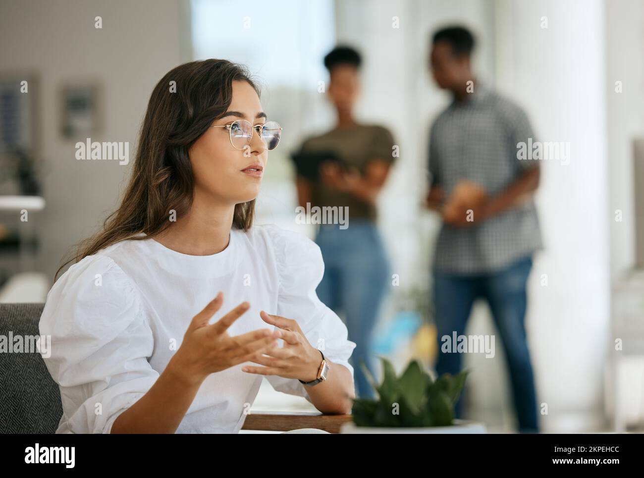 Business woman, creative office and thinking at desk while talking and explaining plan, idea or strategy in a coworking workplace. Designer planning Stock Photo