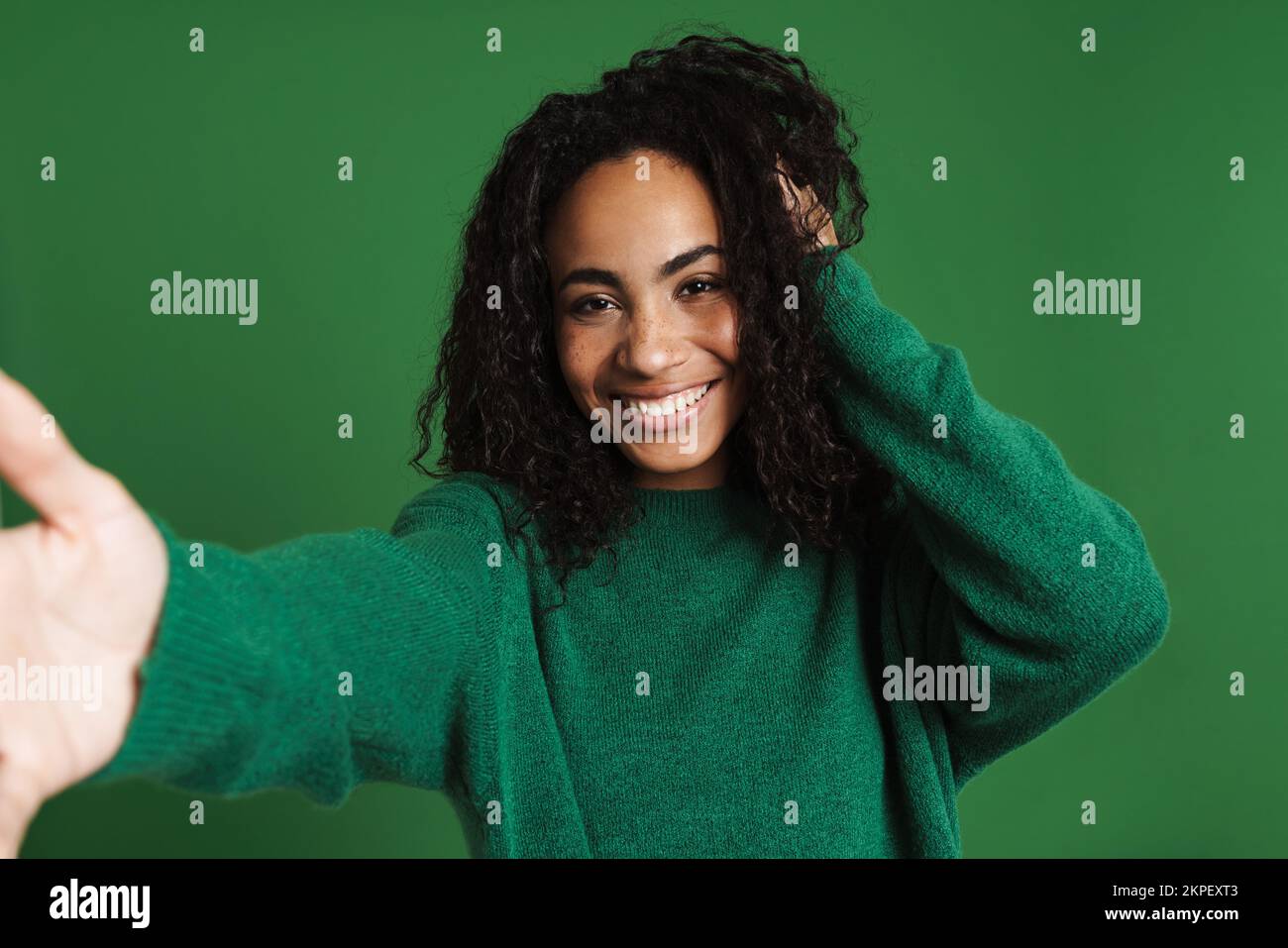 Young black woman wearing sweater laughing while taking selfie photo ...