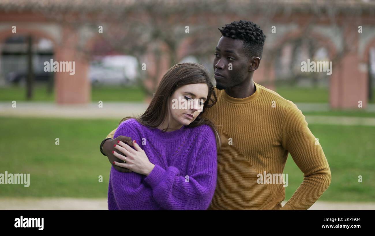 Friend kissing depressed girlfriend in forehead while walking outside together coping and mourning Stock Photo