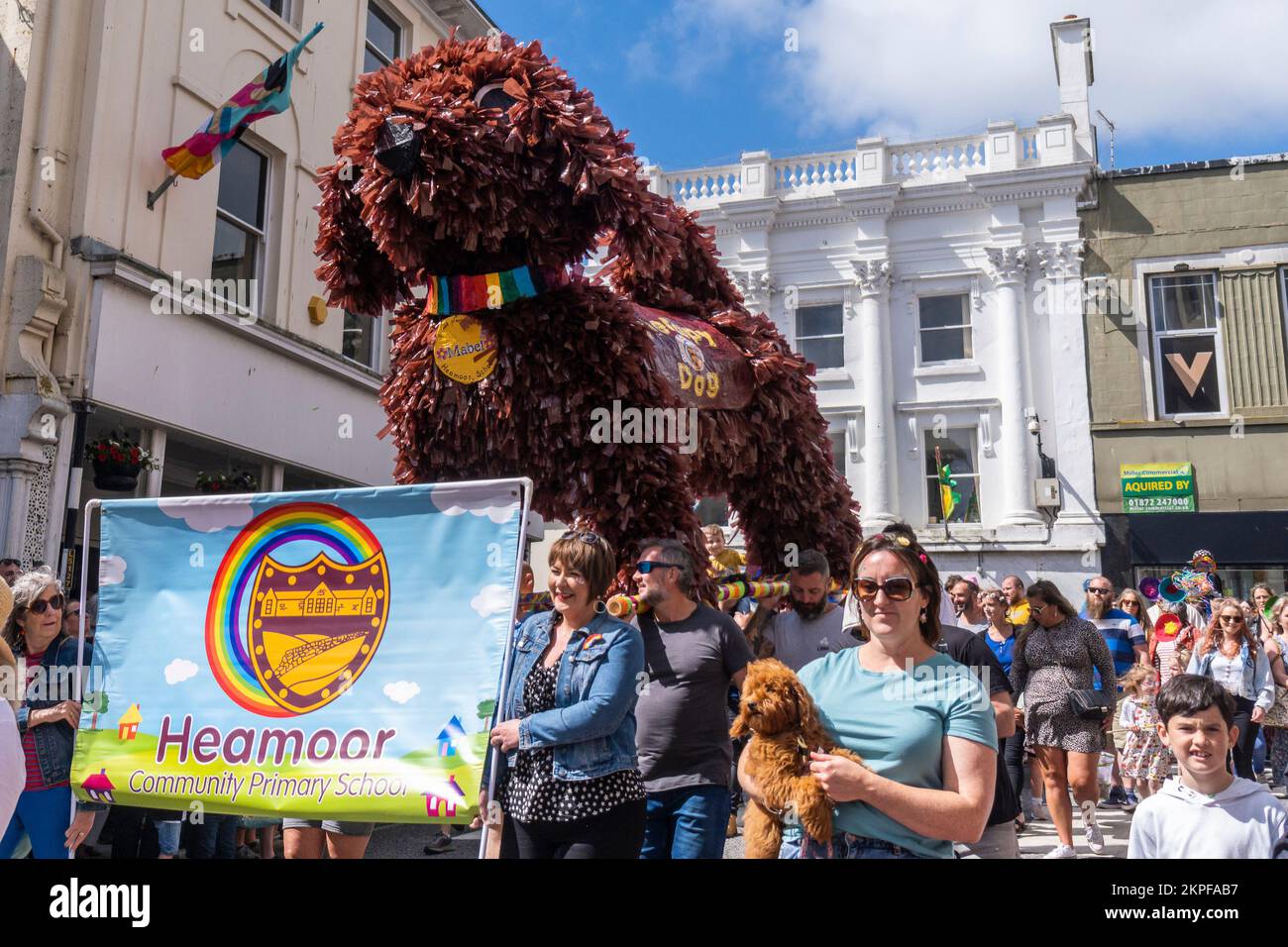 Adults and children from Heamoor Community Primary School parading with their huge sculpture of Mabel a therapy dog through Penzance Cornwall Stock Photo
