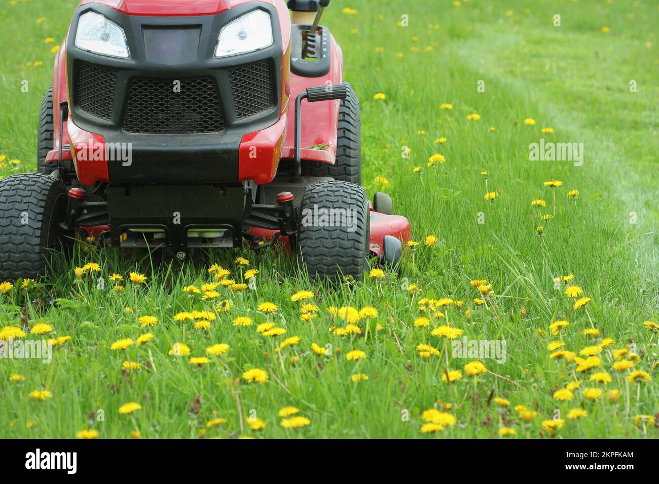 Gardening concept background. Gardener cutting the long grass on a tractor lawn mower . Stock Photo