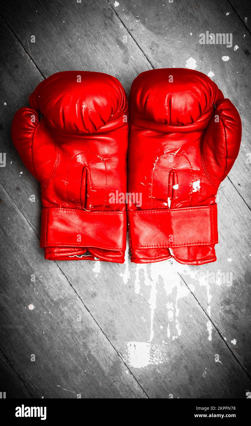 Close-up of vivid red boxing gloves on grey wooden background. Match ring still-life Stock Photo