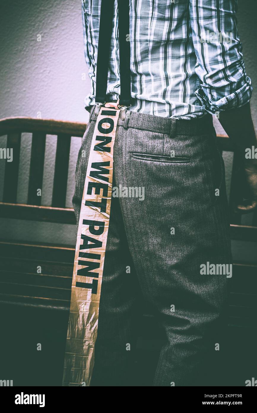 Retro blue tone portrait of a man having a bad day with a series of unfortunate mishaps resulting in wet paint pants. Painterly fortuity Stock Photo