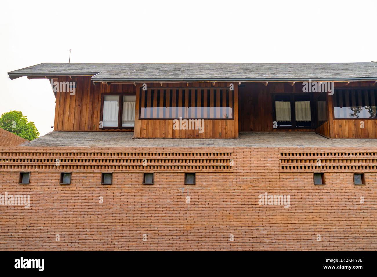 Large long brick house fence with Modern Vintage wood building behind