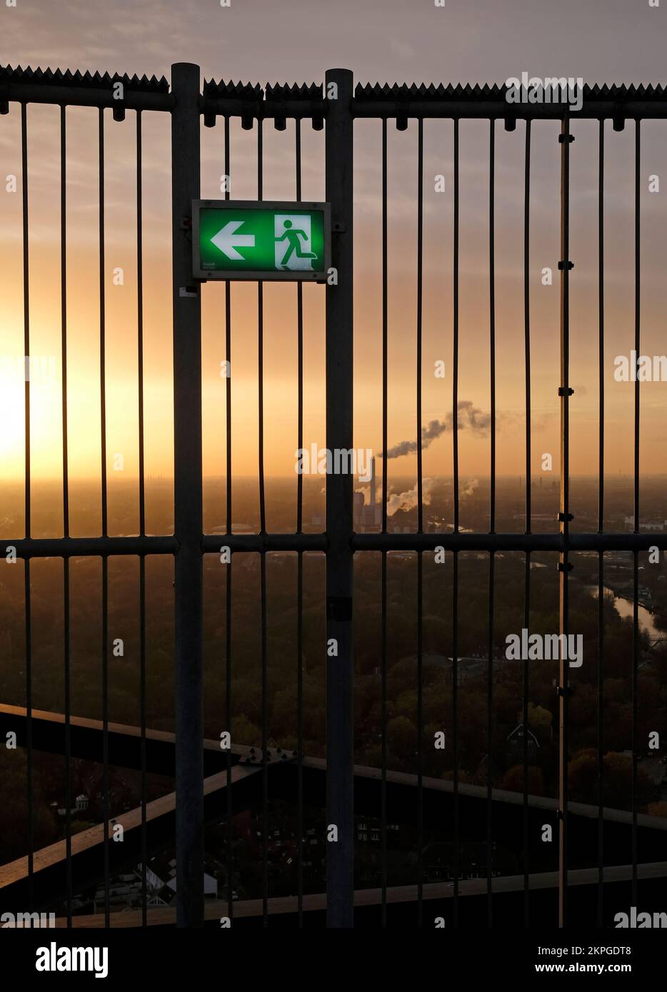 An emergency exit sign with an industrial site in the background during ...