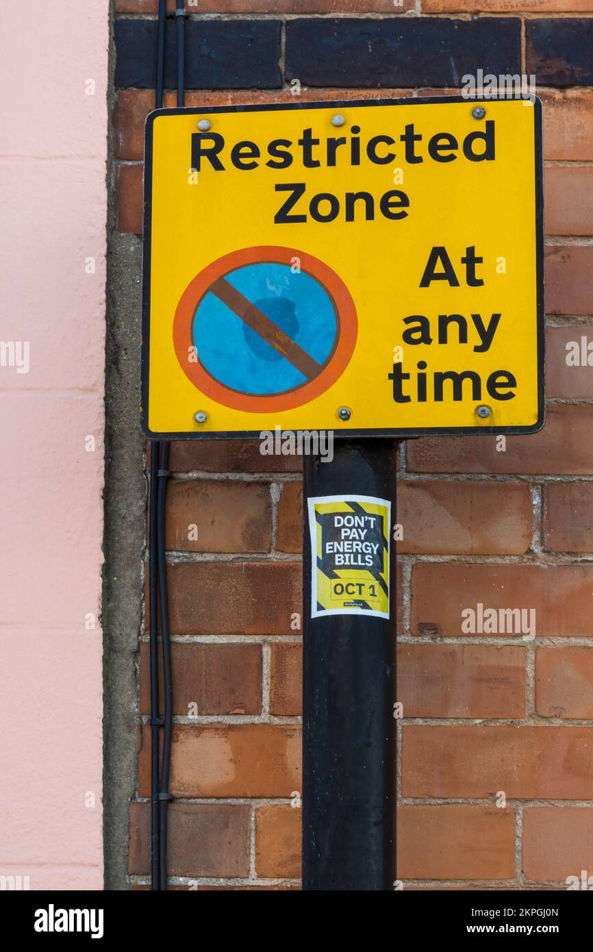 Restricted zone no parking at any time sign with Don't pay energy bills sticker at Weymouth, Dorset UK in October Stock Photo
