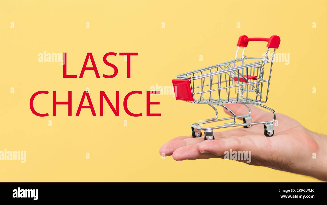 The words last chance next to small shopping grocery cart on male hand