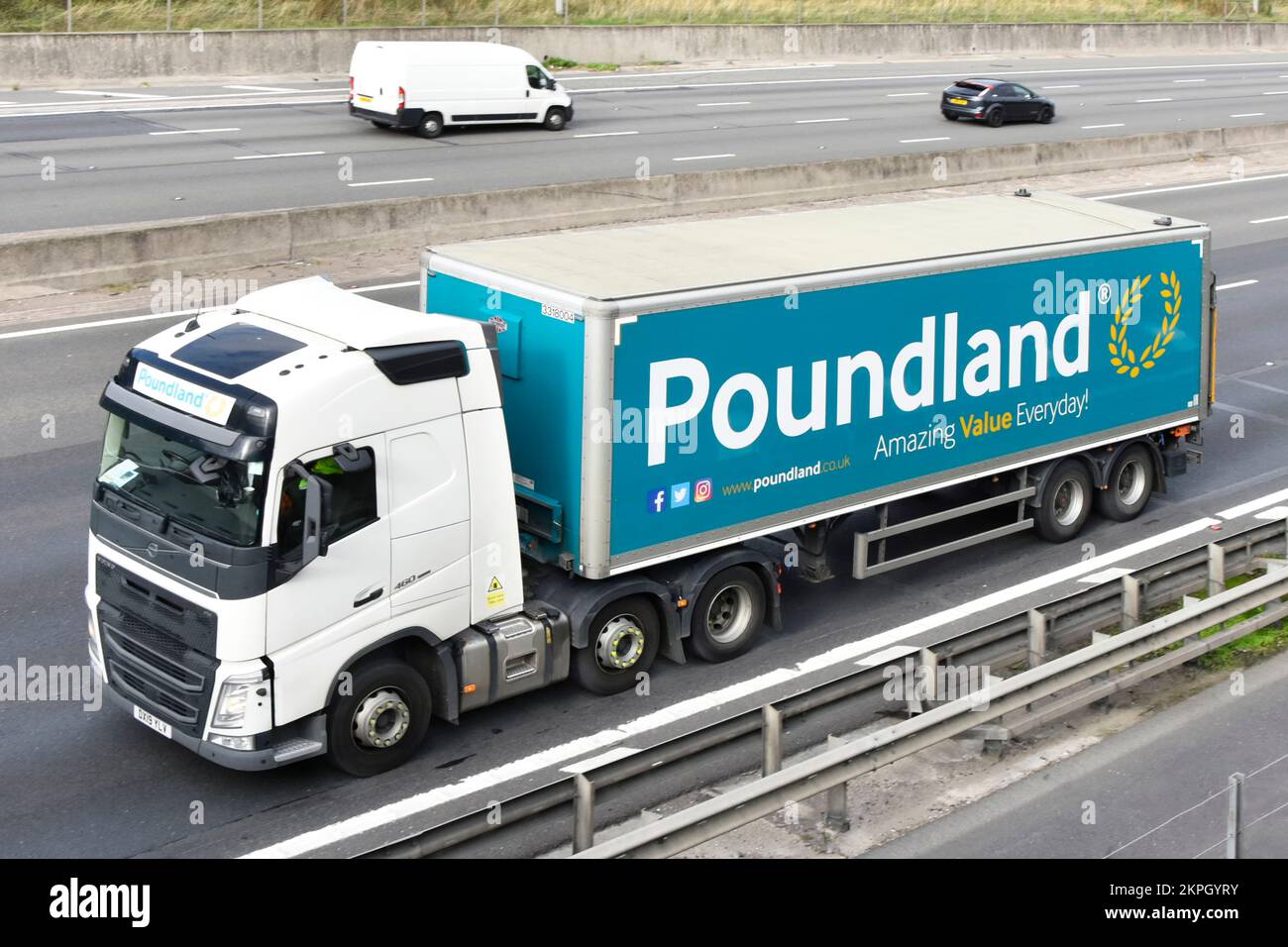 Aerial view white Volvo 460 side front view hgv lorry truck towing articulated trailer advertising for Poundland retail discount business on UK road Stock Photo
