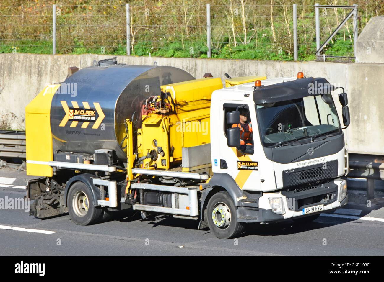 Volvo lorry truck chassis cab & specialized bitumen tank equipment used for road spraying commercial vehicle driver in cab driving on UK motorway road Stock Photo