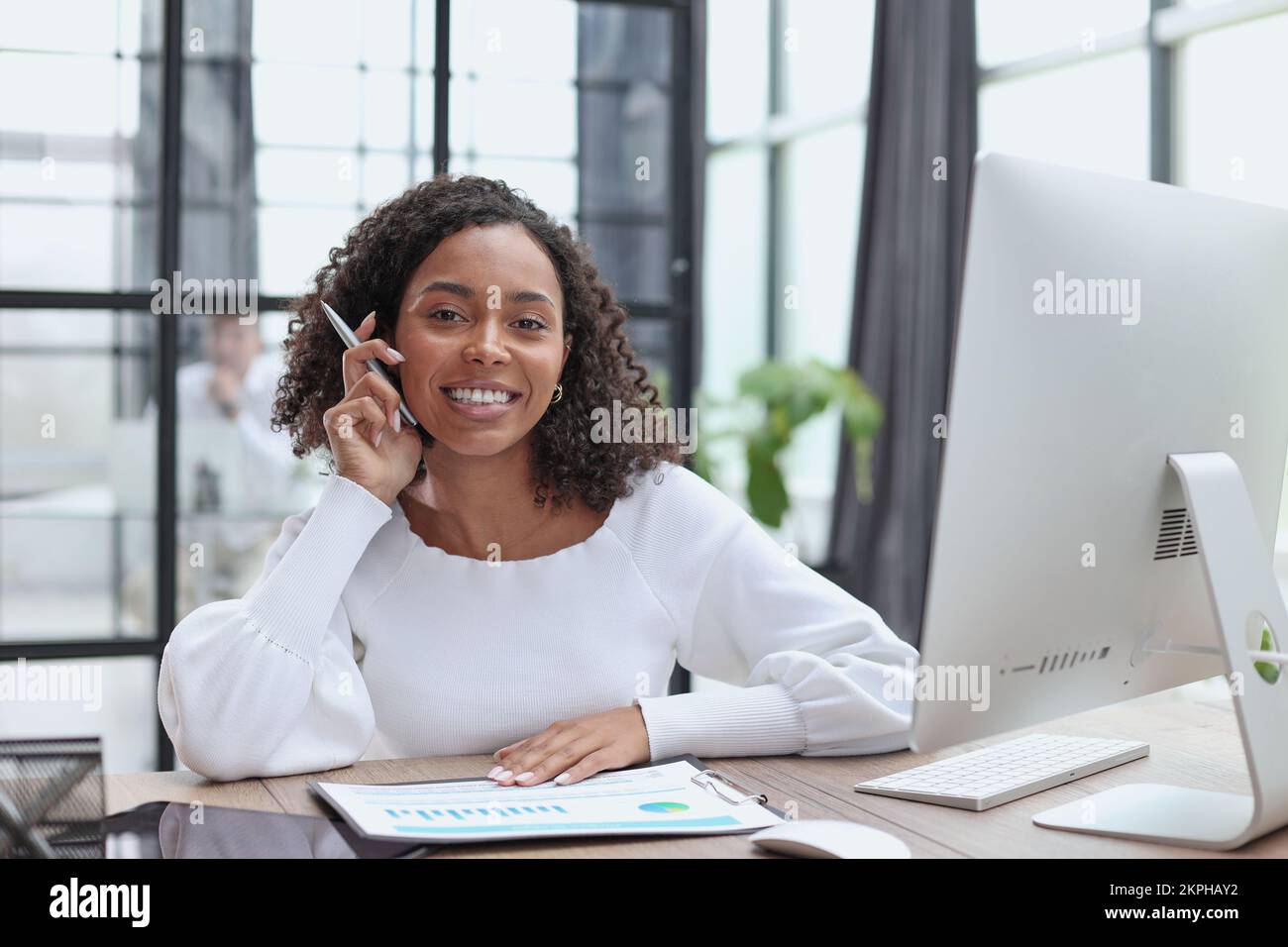 Waist up portrait of cheerful young mixed race female with curly hair Stock Photo