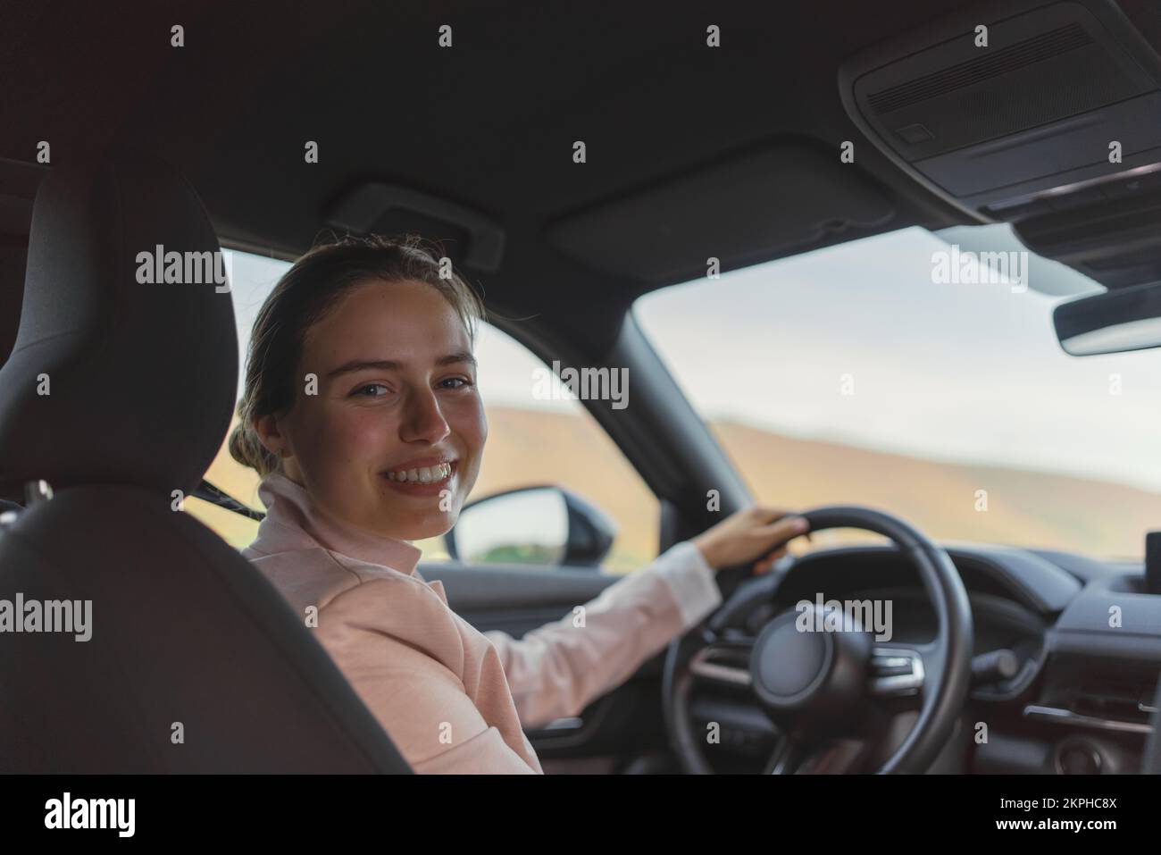 Rear view of young woman driving her electric car. Stock Photo