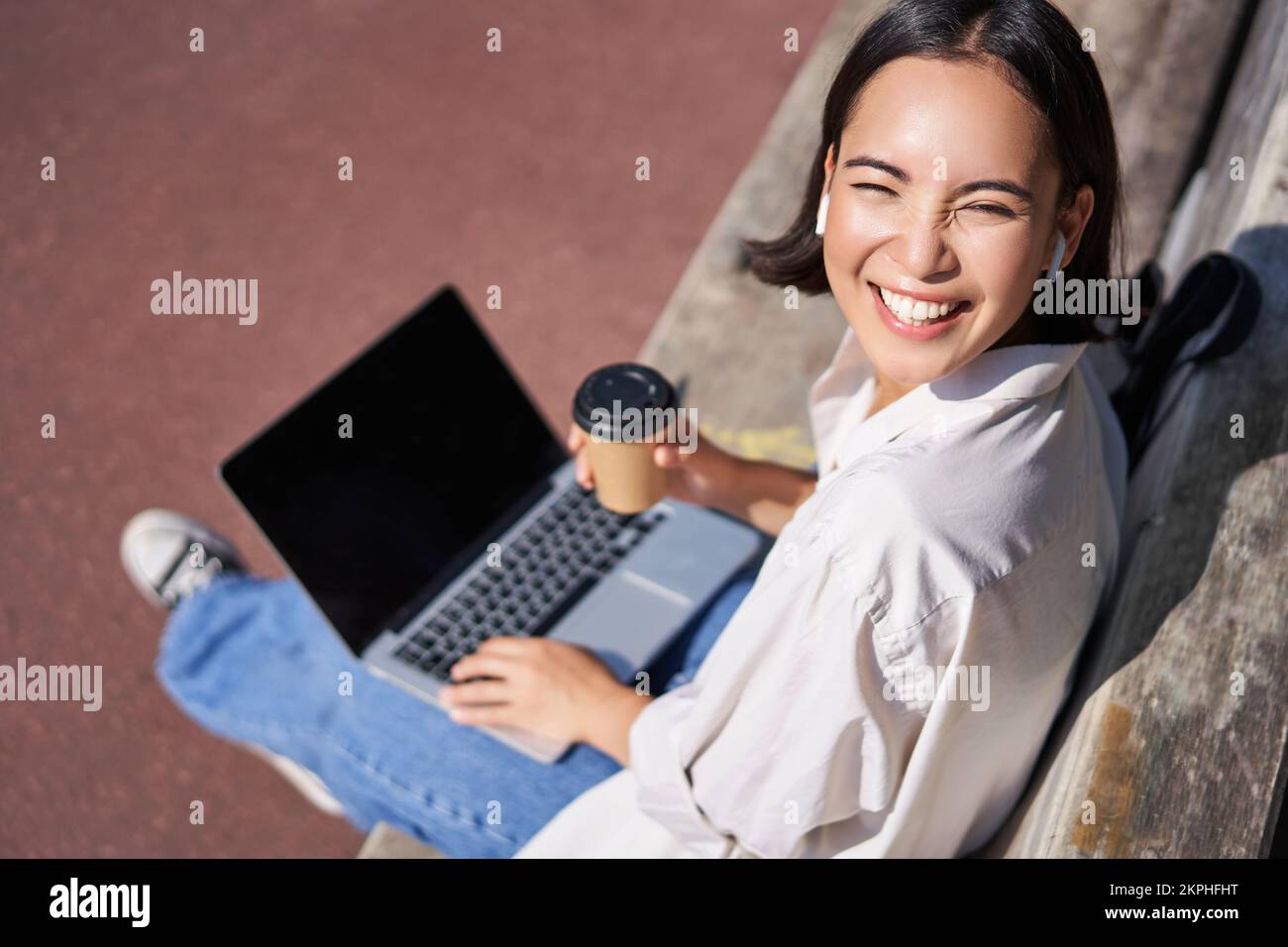 Beautiful young asian female student, sitting with laptop on bench in ...