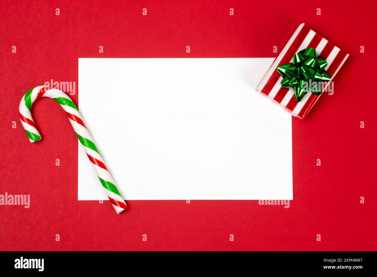 https://c8.alamy.com/comp/2KPHM87/christmas-letter-mock-up-blank-white-empty-page-on-red-background-with-a-red-and-green-candy-cane-and-a-gift-box-postcard-greetings-and-thank-you-2KPHM87.jpg